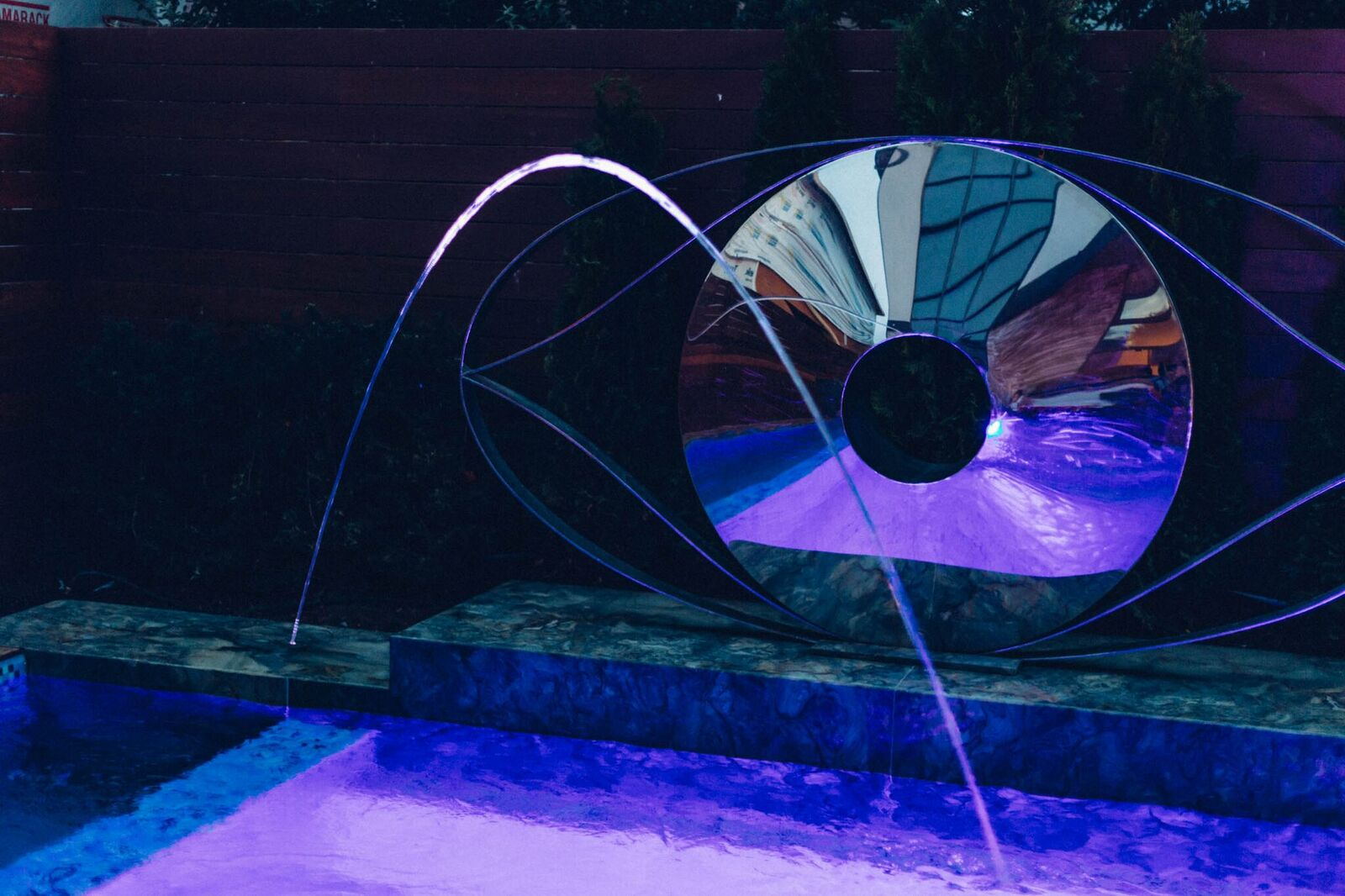 Illuminated stainless steel water fountain operating at night